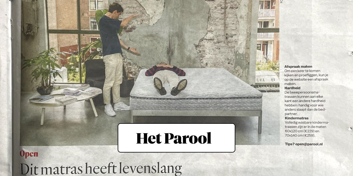 Man liggend op een Ubed matras in een industriële ruimte met planten en salontafel op de voorgrond.